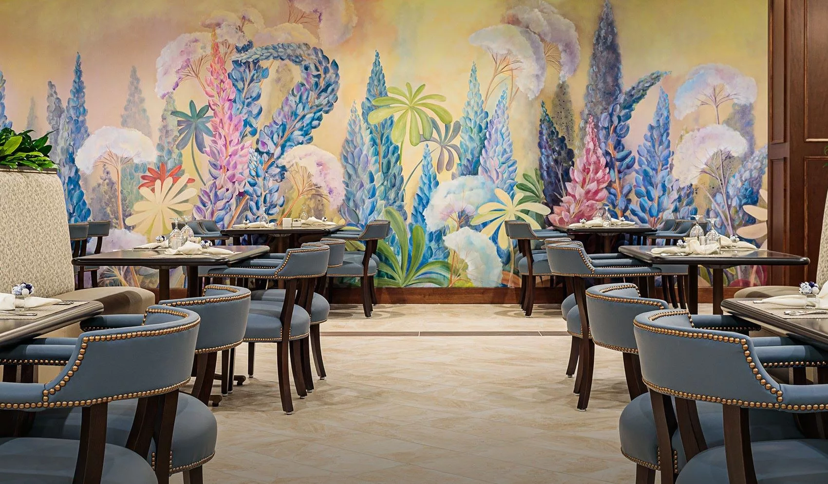 A beautifully decorated restaurant interior featuring a vibrant, colorful mural and elegant dining furniture.