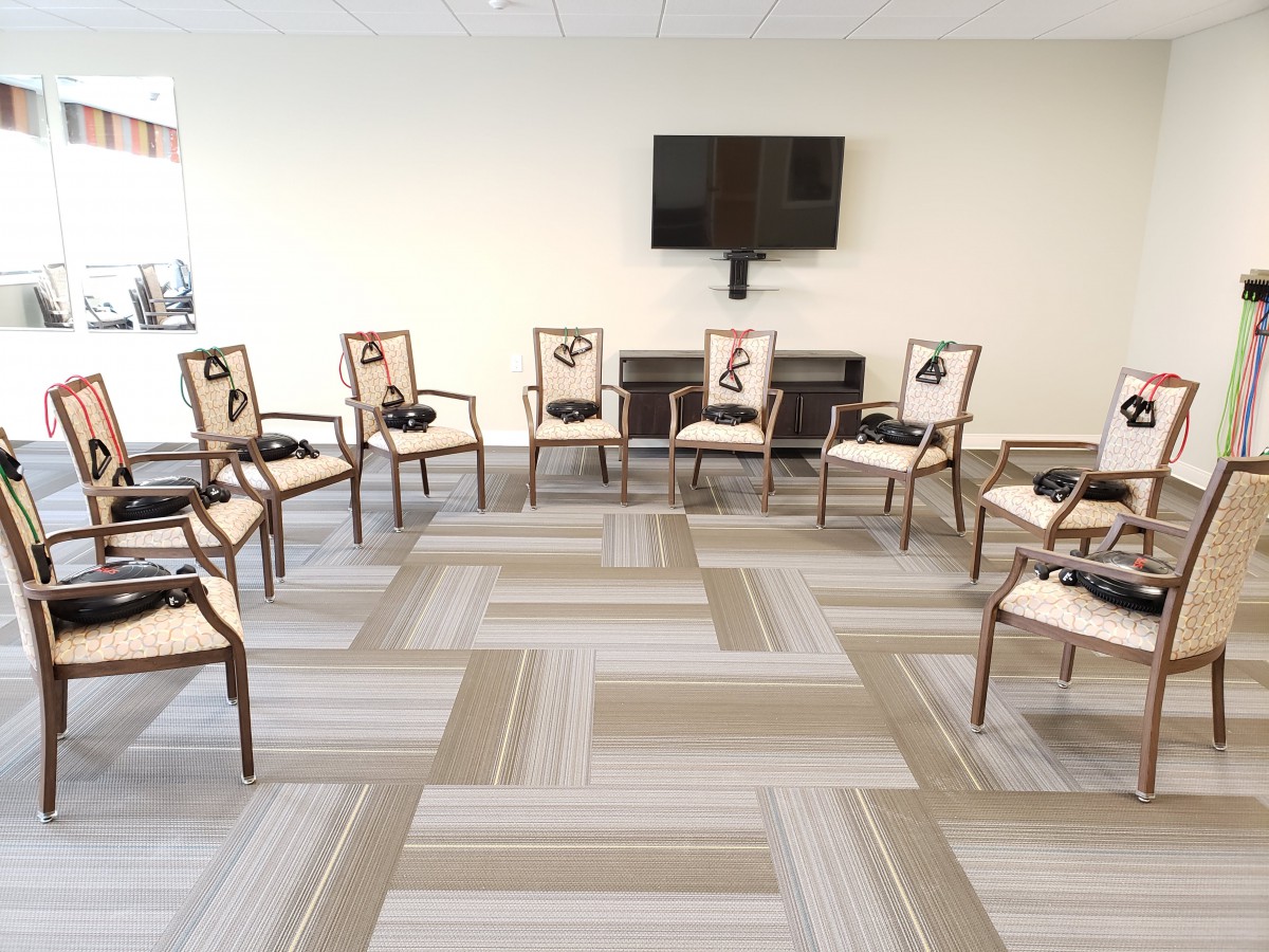A meeting room with chairs arranged in a circle and a television on the wall.