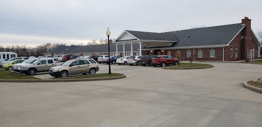 A view of a building with cars parked in front on a cloudy day.