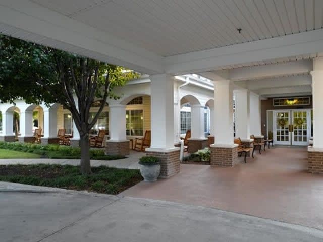 A covered outdoor seating area with columns and landscaping.