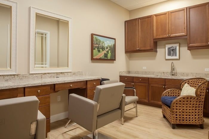 A cozy office or waiting room with chairs, a desk, and cabinets, decorated with artwork on the walls.