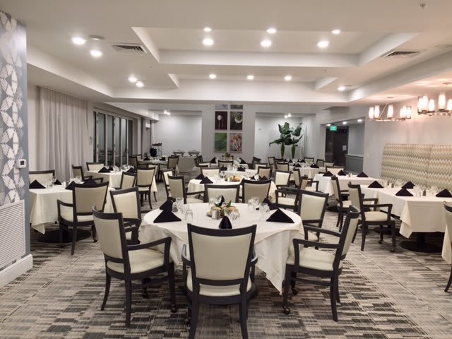 A well-organized banquet hall with elegantly set tables and chairs, ready for an event.