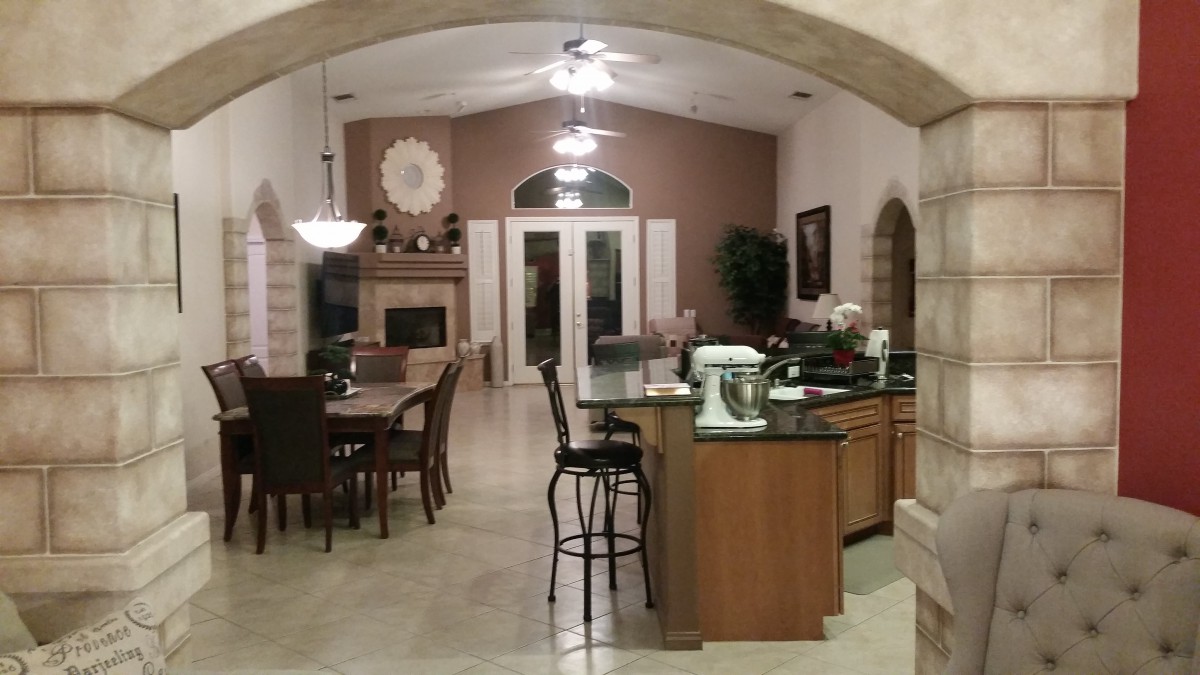 A spacious kitchen and dining area with an open floor plan, featuring a central island, bar stools, and a cozy fireplace.