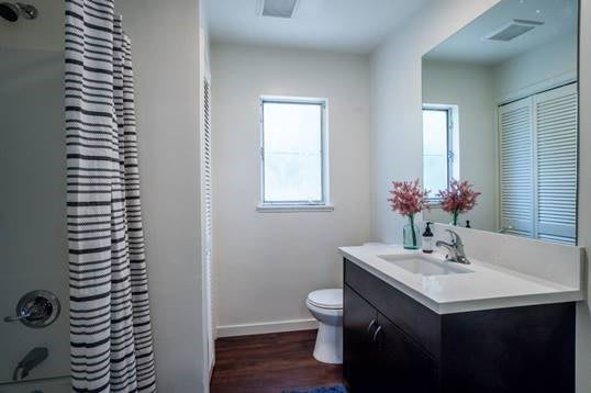A modern bathroom with a sink, mirror, and toilet, featuring minimal decor.