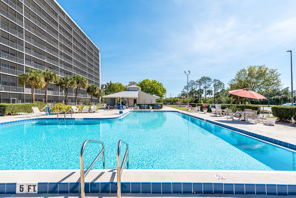 A sunny day at a hotel's outdoor swimming pool with lounge chairs and umbrellas.