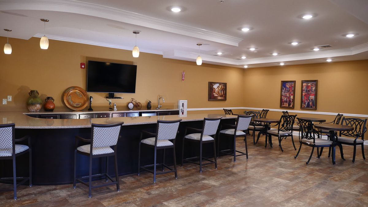 A modern bar area with seating, a television, and stylish decor.