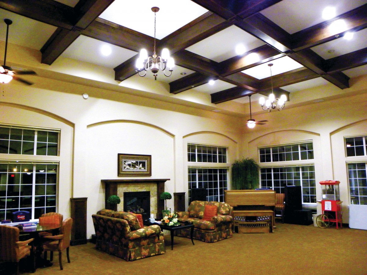 A spacious living room with a coffered ceiling, cozy seating area, and a piano.