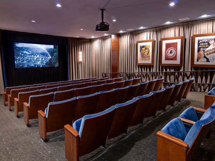An empty theater with rows of seating and a screen displaying an image.