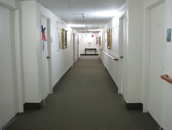 A well-lit hallway with multiple doors and framed pictures on the walls.