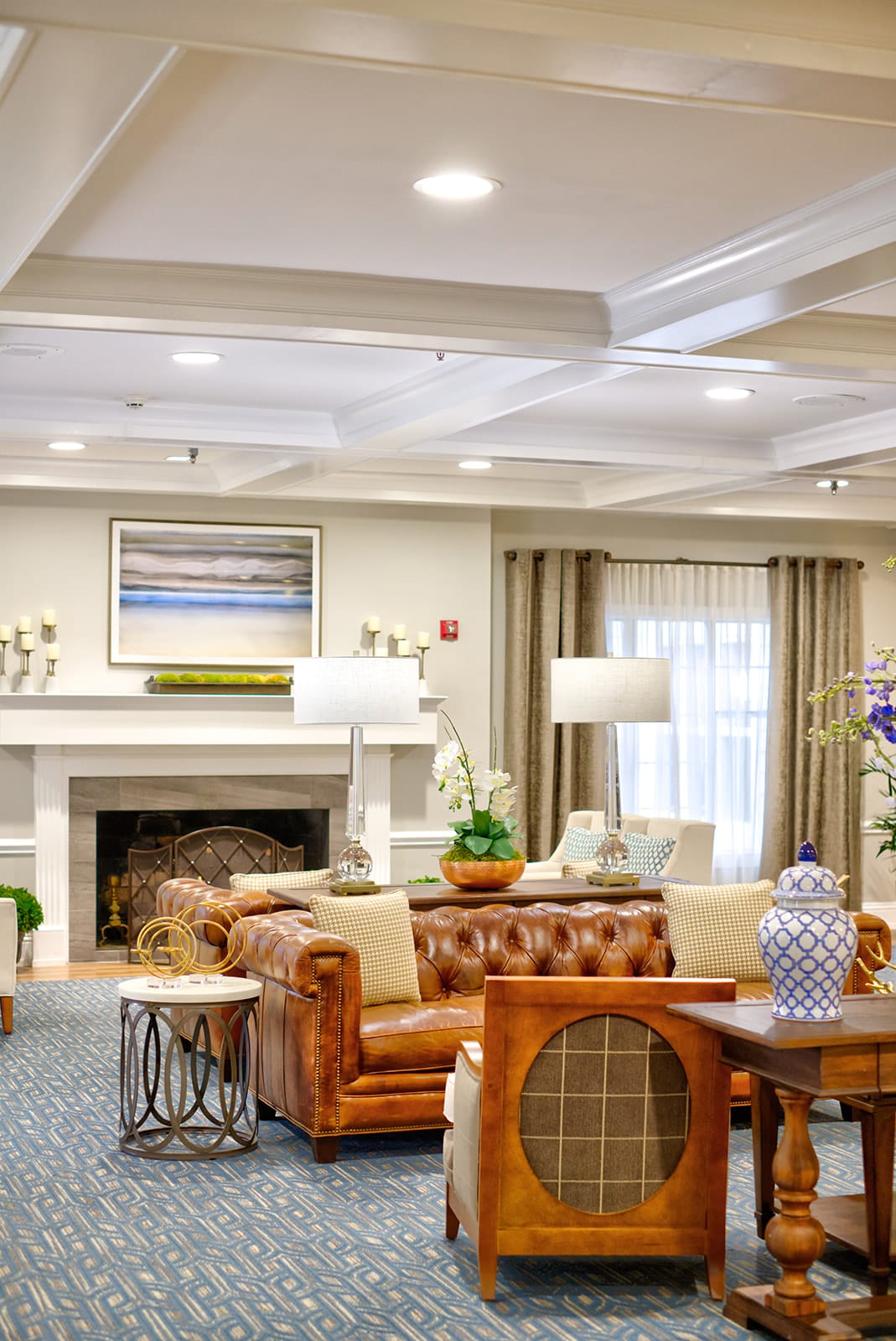 A well-decorated living room featuring a leather sofa, fireplace, and elegant lighting.