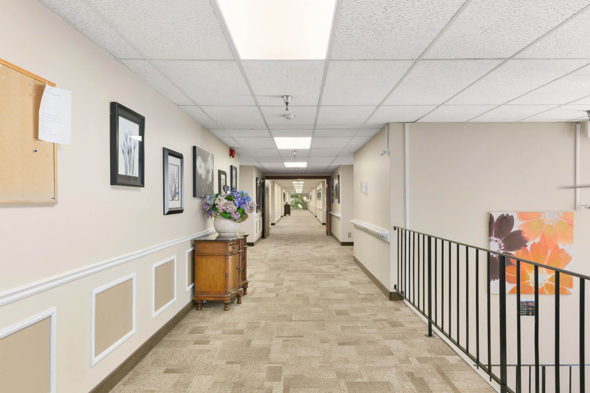 A well-lit hallway with artwork on the walls and a carpeted floor.