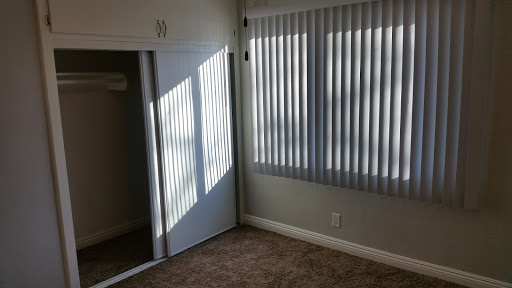 A well-lit empty room featuring vertical blinds and carpeted flooring.