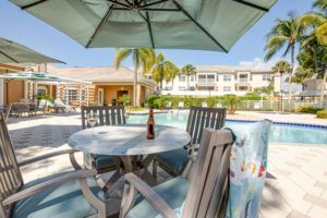 A relaxing poolside setup with chairs, a table, and an umbrella on a sunny day at a resort.
