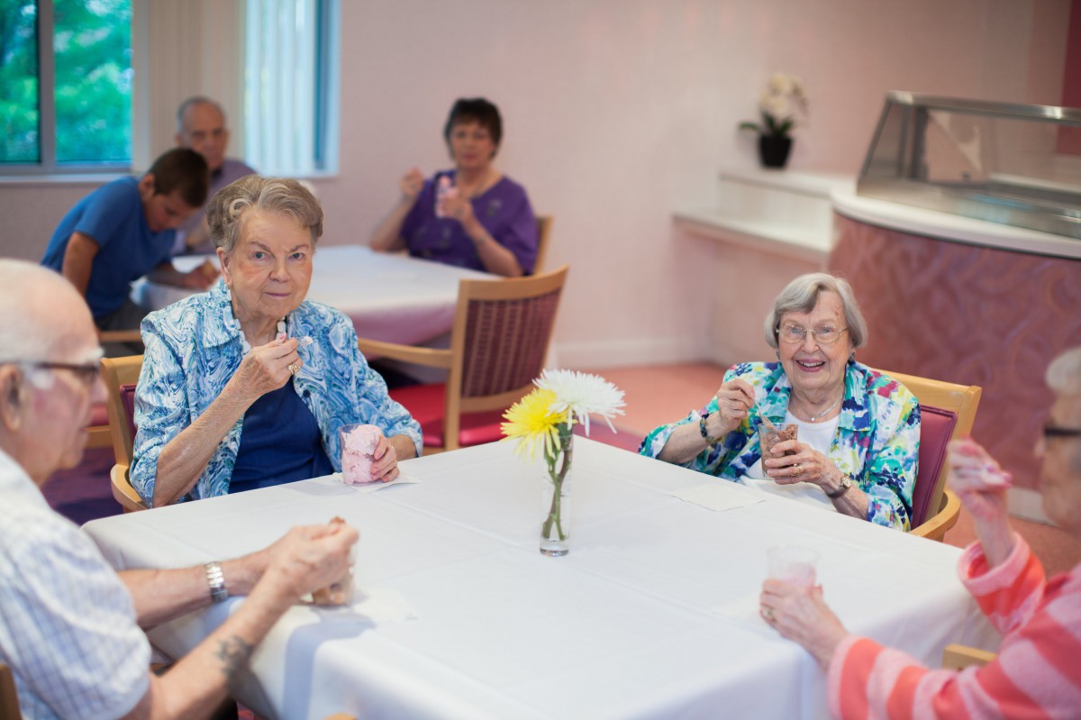 A group of seniors enjoying a social gathering and refreshments indoors.