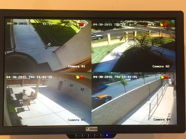 A monitor displaying four CCTV camera feeds of an outdoor area.