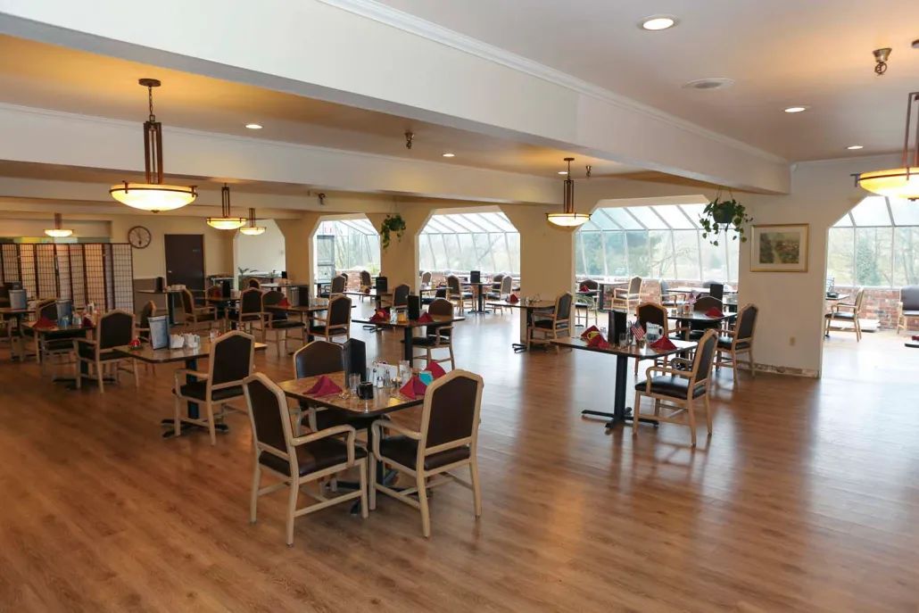 A spacious dining area with neatly arranged tables and chairs, well-lit by large windows.
