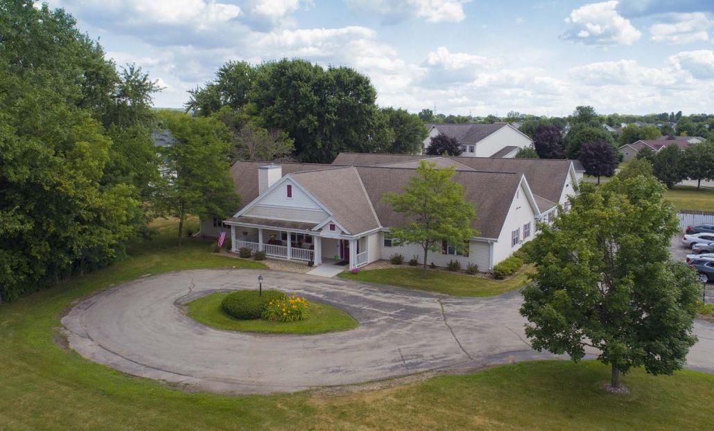 Aerial view of a residential building with a circular driveway and surrounding trees.