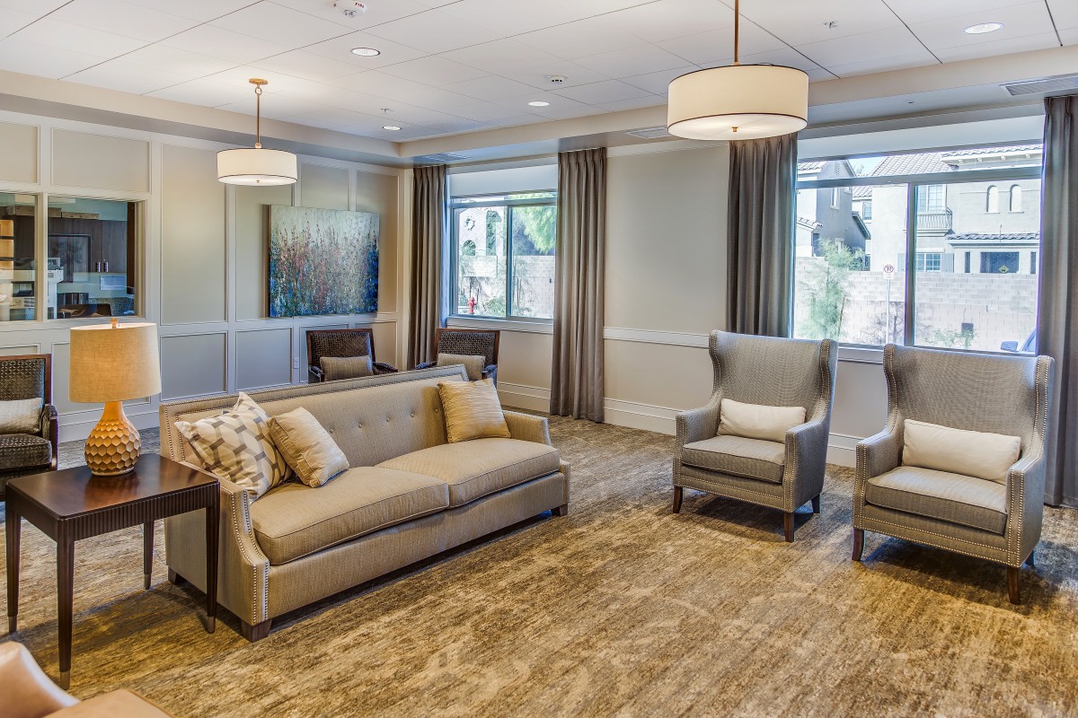 A cozy living room with a sofa, armchairs, and large windows.