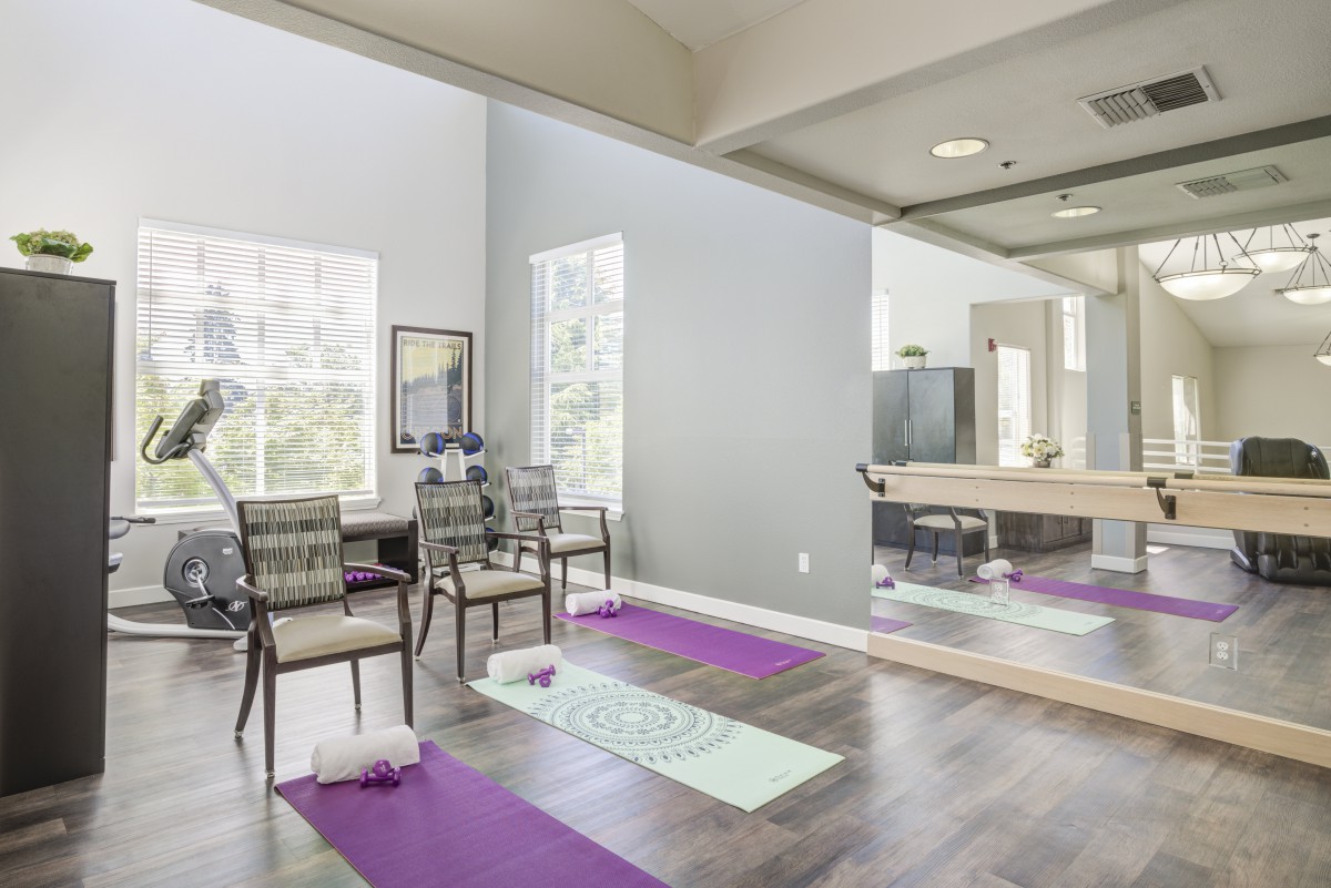 A bright and spacious yoga studio with exercise mats and mirrors.