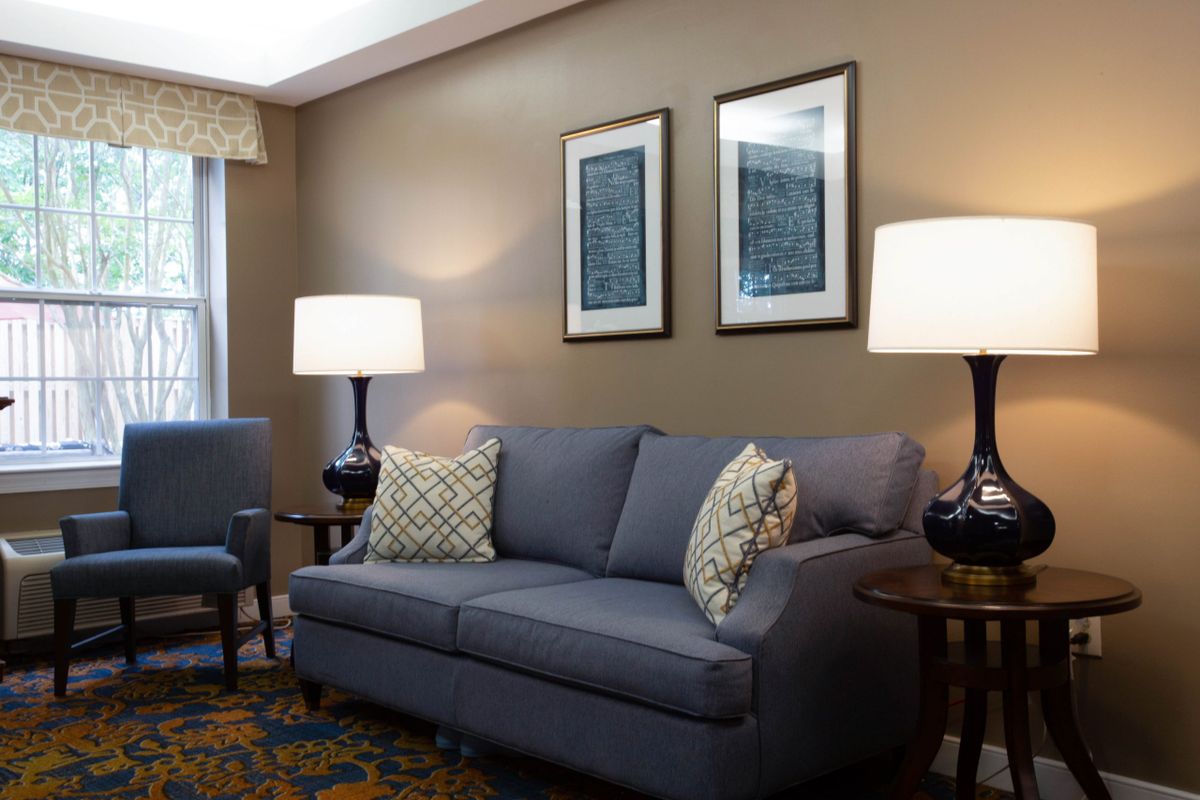 A cozy living room with a gray sofa, decorative pillows, two table lamps, and framed wall art.