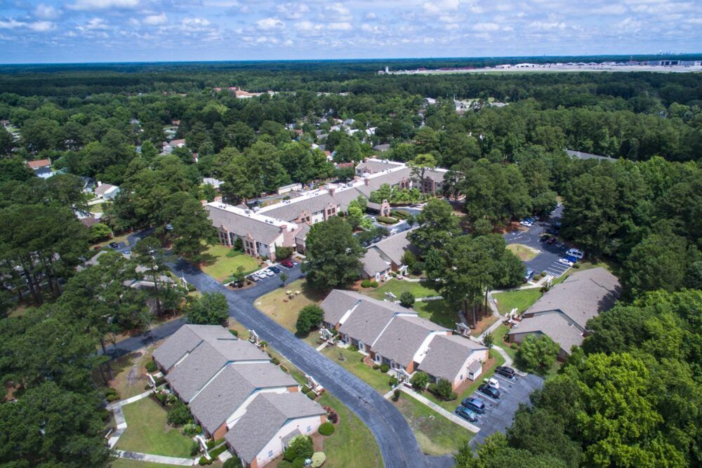 Aerial view of a housing complex surrounded by trees and roads.