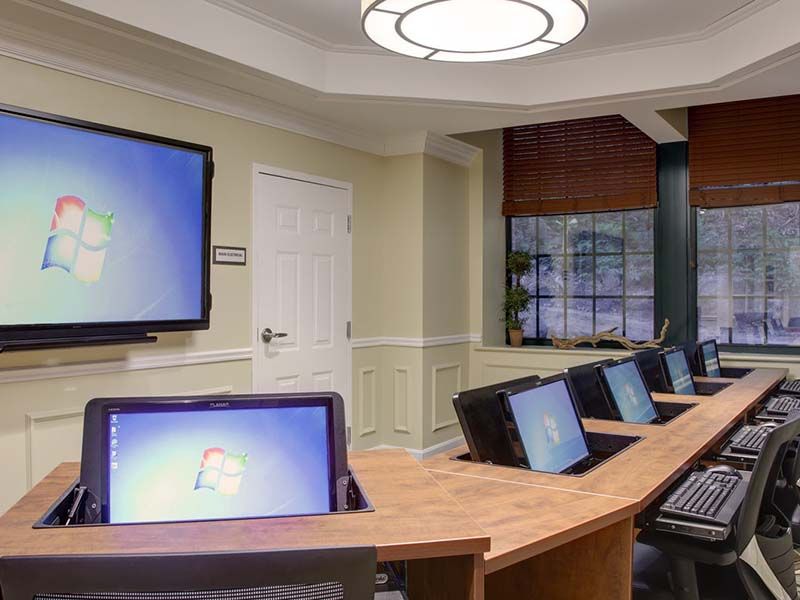 A modern conference room equipped with several computers and a large display screen.