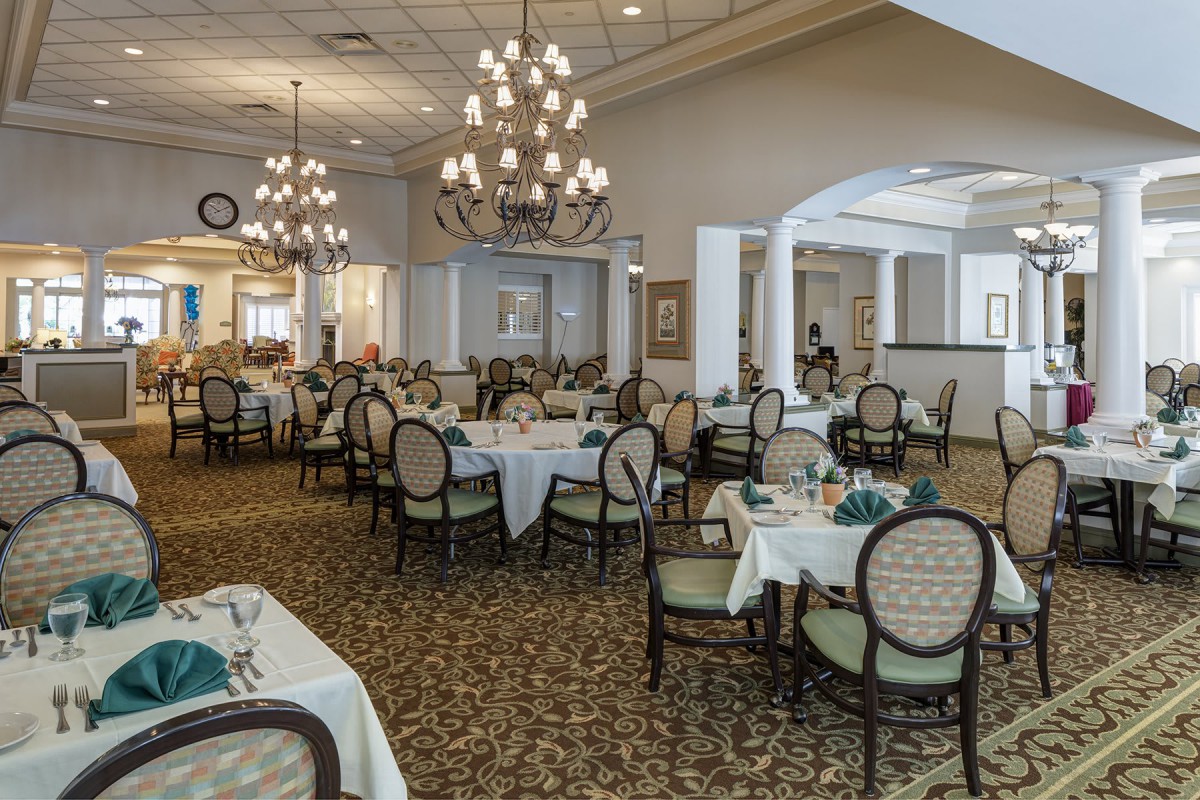 An elegant dining room with neatly arranged tables and chairs, adorned with chandeliers.