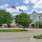 A building with American and state flags flying outside, surrounded by trees on a clear day.