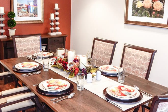 A well-decorated dining table with elegant place settings, featuring candles and a floral centerpiece.