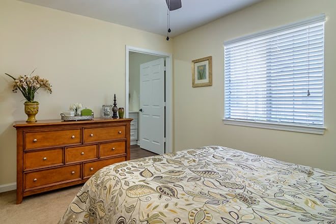 A cozy bedroom with a dresser and a bed featuring patterned bedding.