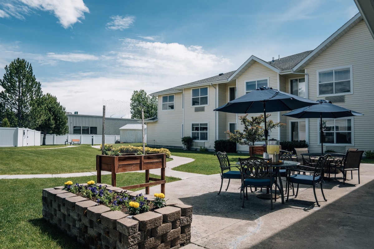 A sunny day in a courtyard featuring patio furniture and a garden area.