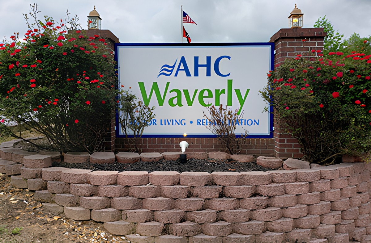 Entrance sign for AHC Waverly, framed by a brick wall and flowers.