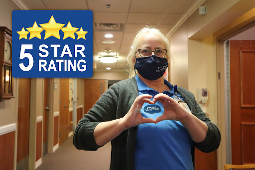 A dedicated healthcare worker proudly displays a heart shape, celebrating a five-star rating for their facility.