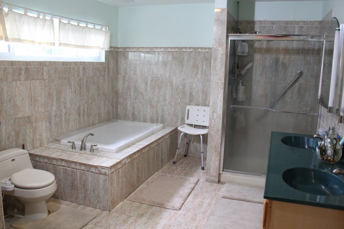 A spacious modern bathroom featuring a bathtub, separate shower area, and tiled walls.