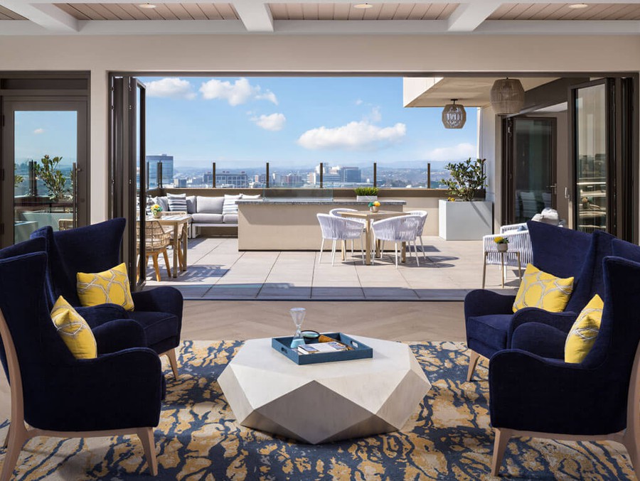 A modern living area opens up to a spacious outdoor terrace with a stunning city view.