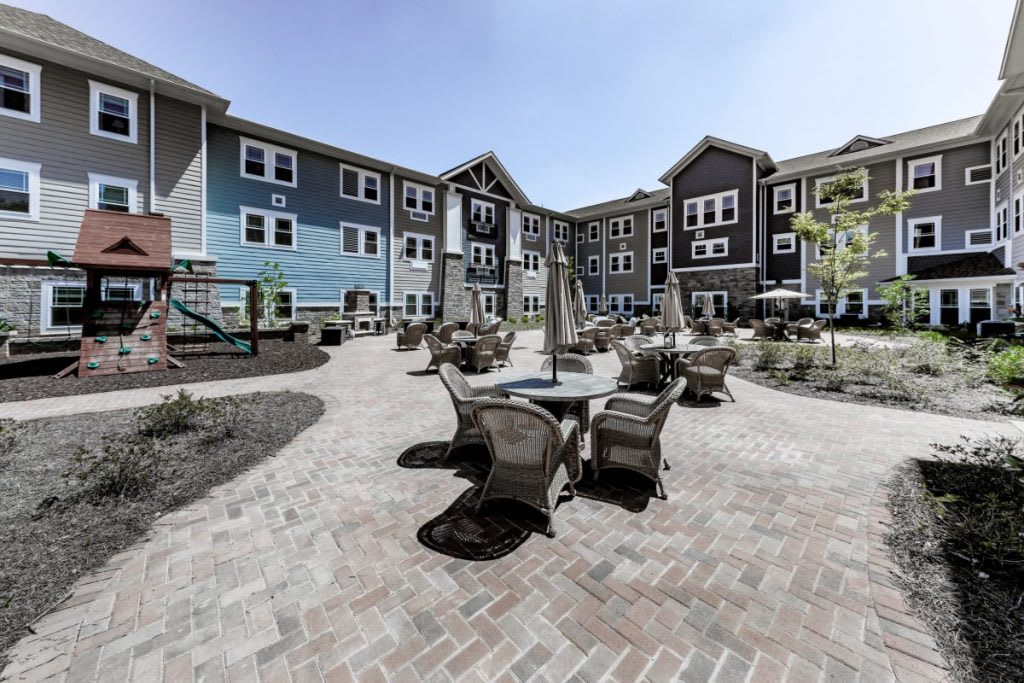 A modern apartment complex with a spacious courtyard featuring outdoor seating and well-maintained landscaping.