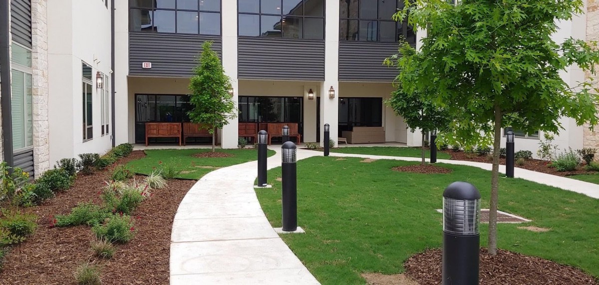 A modern building entrance with a curved walkway and outdoor landscaping.