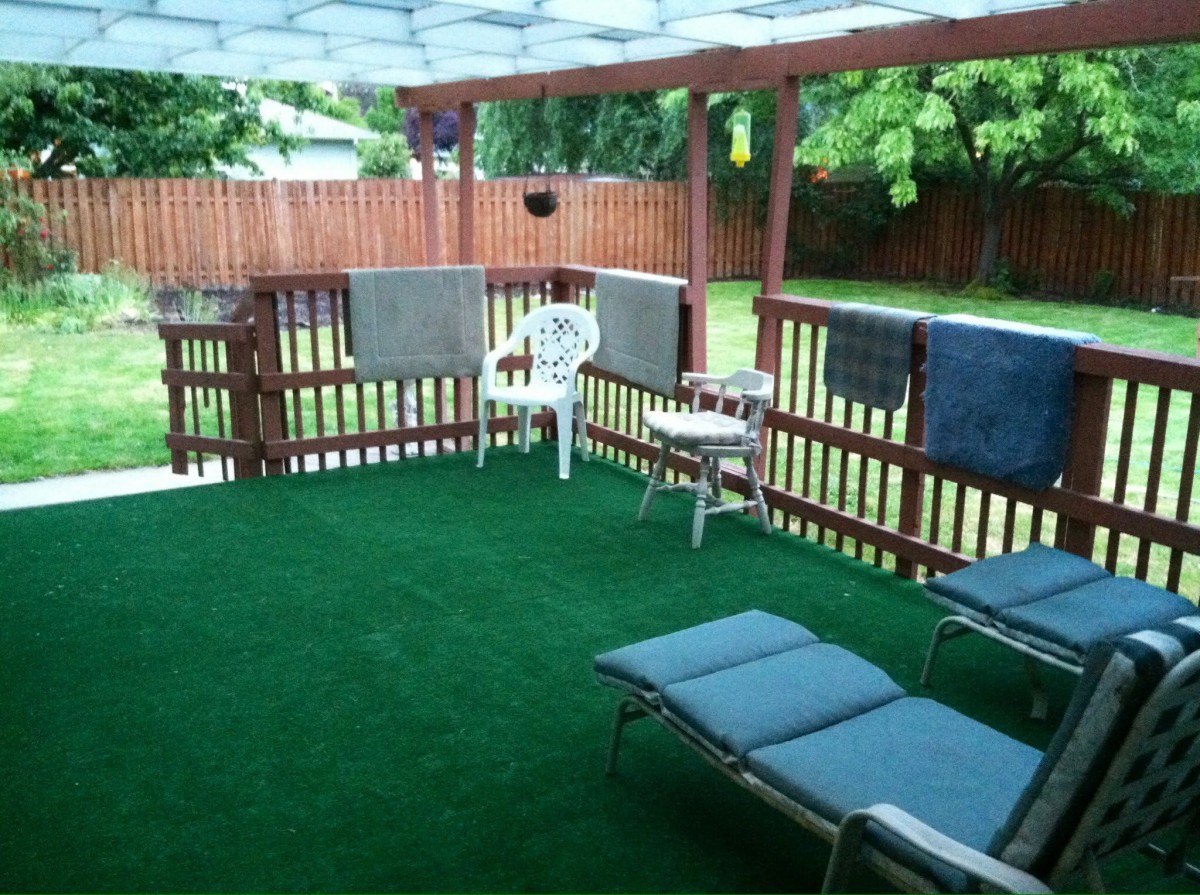 A cozy outdoor patio area with sunbathing chairs and towels hanging on the railing.