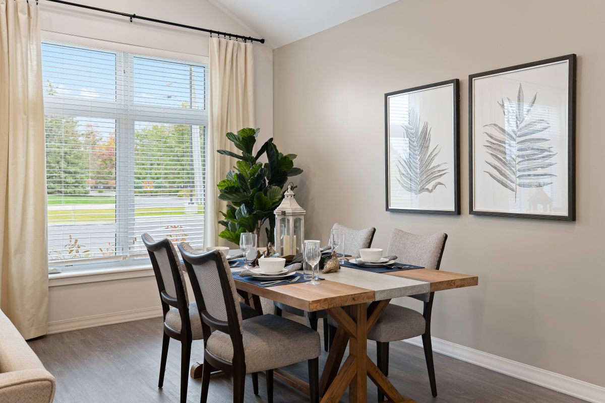 A well-appointed dining room with a wooden table, upholstered chairs, and natural light streaming through the window.