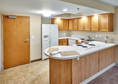 A modern kitchen with wooden cabinets, a white refrigerator, and an island countertop featuring a built-in stove.