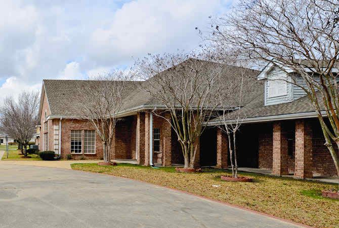 A suburban brick house with a driveway and trees.