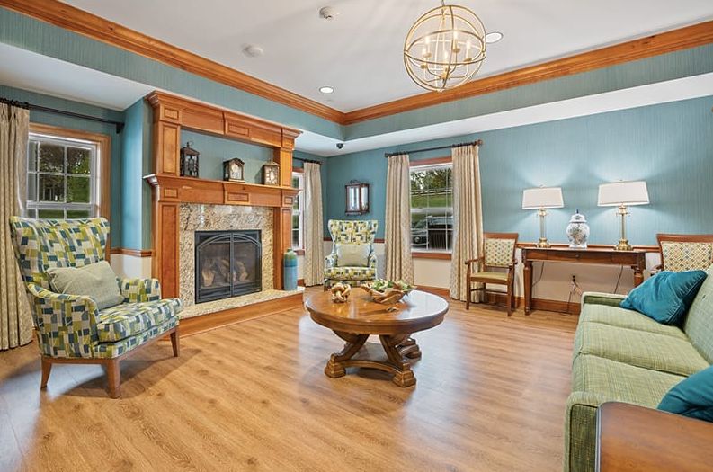 A cozy living room with a fireplace and stylish decor, featuring wood flooring, blue walls, and elegant furnishings.