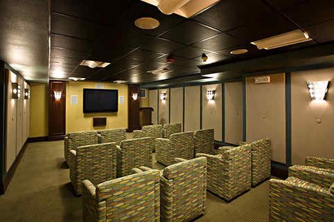 A cozy home theater setup with multiple cushioned chairs facing a large TV screen.