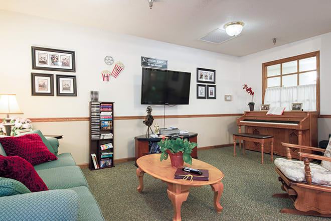 A cozy living room featuring a television, piano, and various decorations.