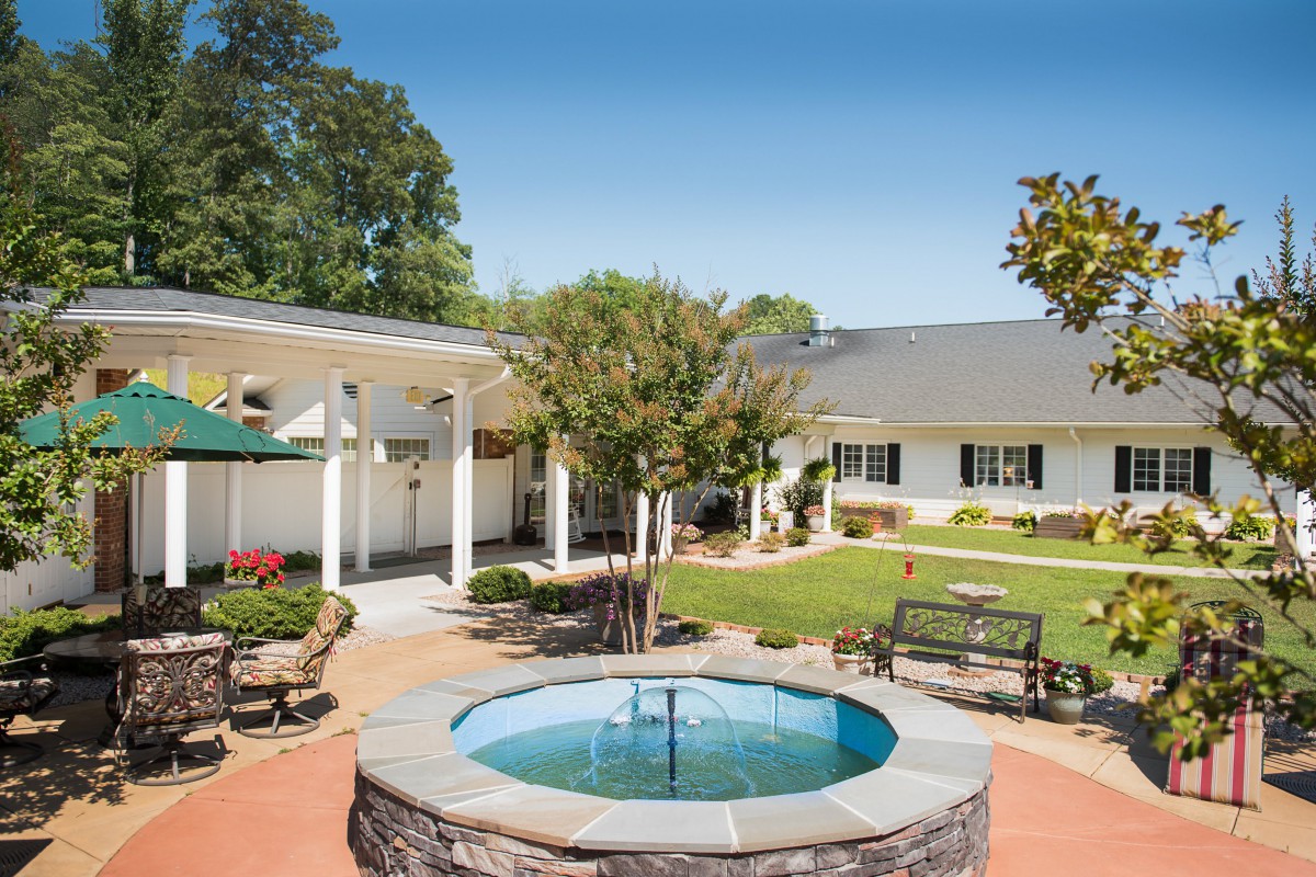 A serene courtyard featuring a fountain, surrounded by benches and lush landscaping.