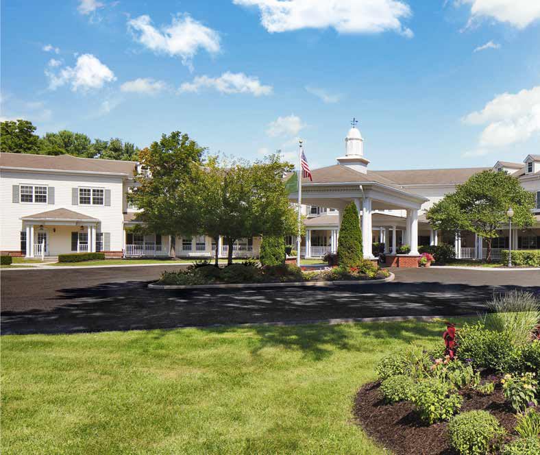 A scenic view of a large building surrounded by well-maintained lawns and trees under a partly cloudy sky.