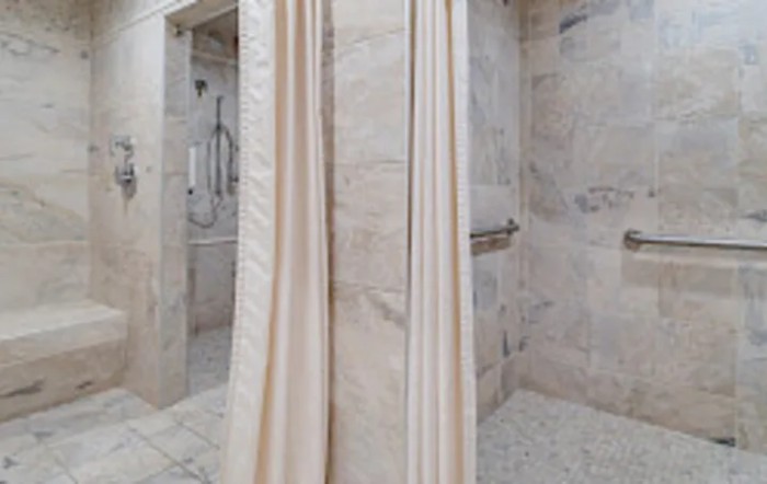 A modern bathroom with a tiled shower and curtain.