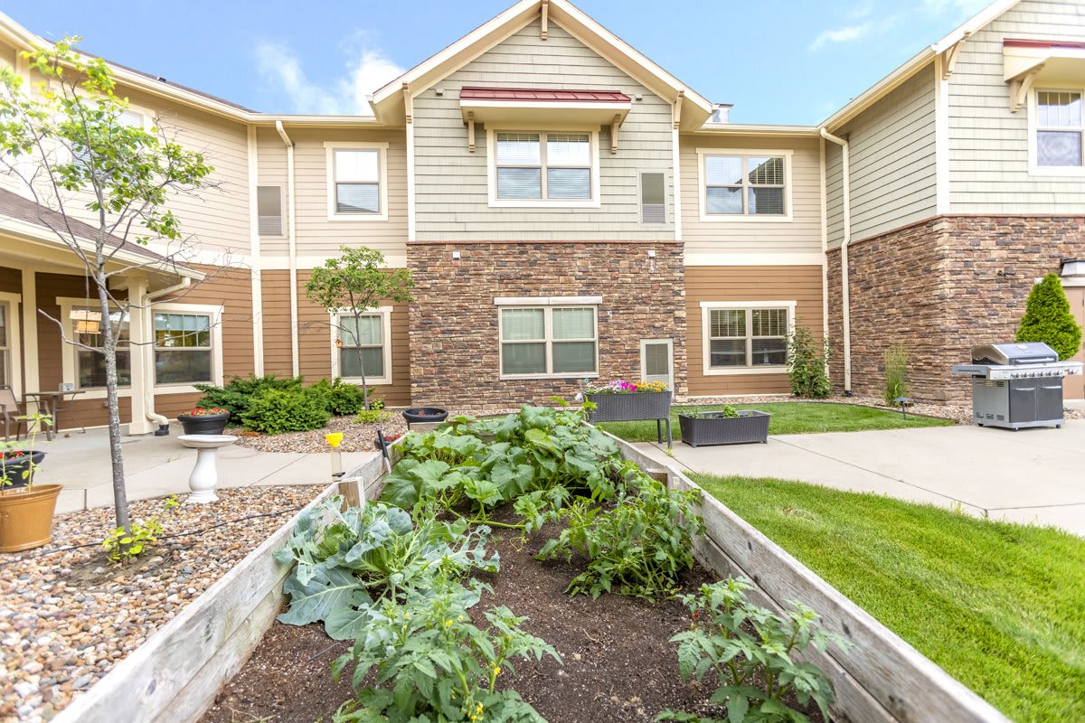 A two-story residential building with a brick exterior, featuring a landscaped garden in the foreground.