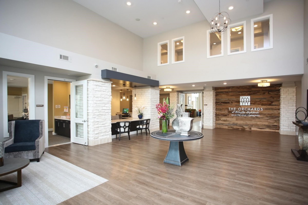 A modern lobby with stylish decor and wood flooring, featuring a reception desk and decorative plants.