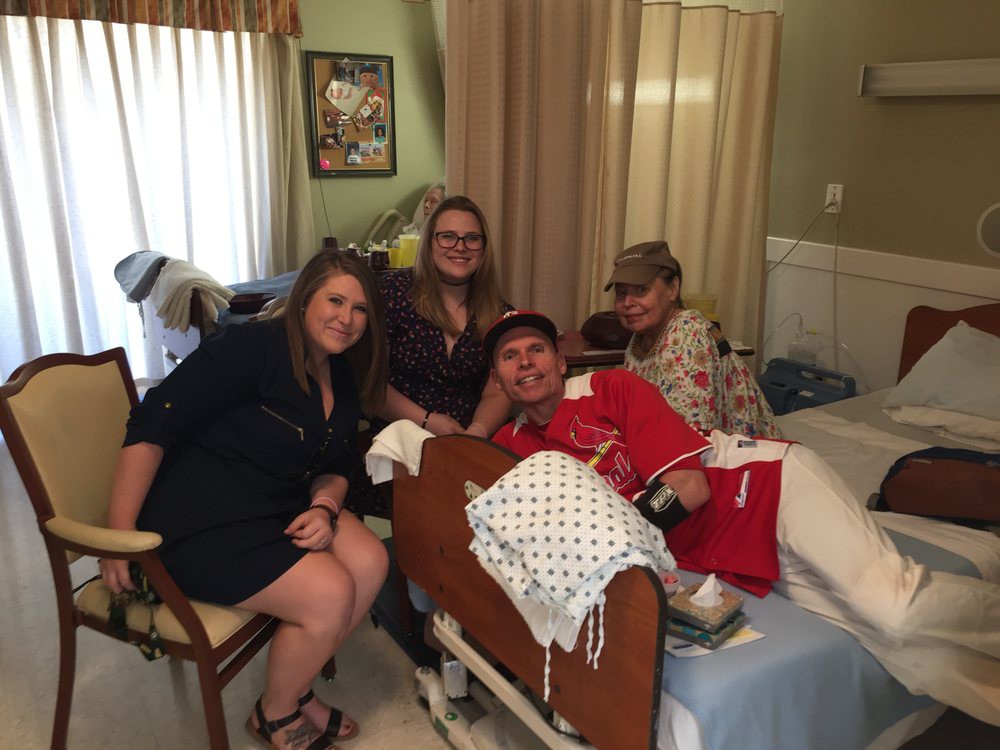 A group of people visiting a patient in the hospital, sharing smiles and support.